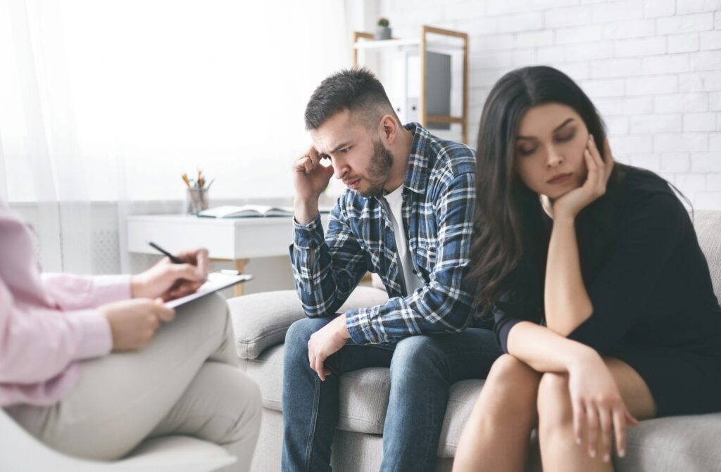 Stressed couple sitting separately at family counselor office